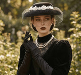 Load image into Gallery viewer, Black felt vintage-inspired hat with veil and white floral embellishment, worn by a model with pearls and gloves.